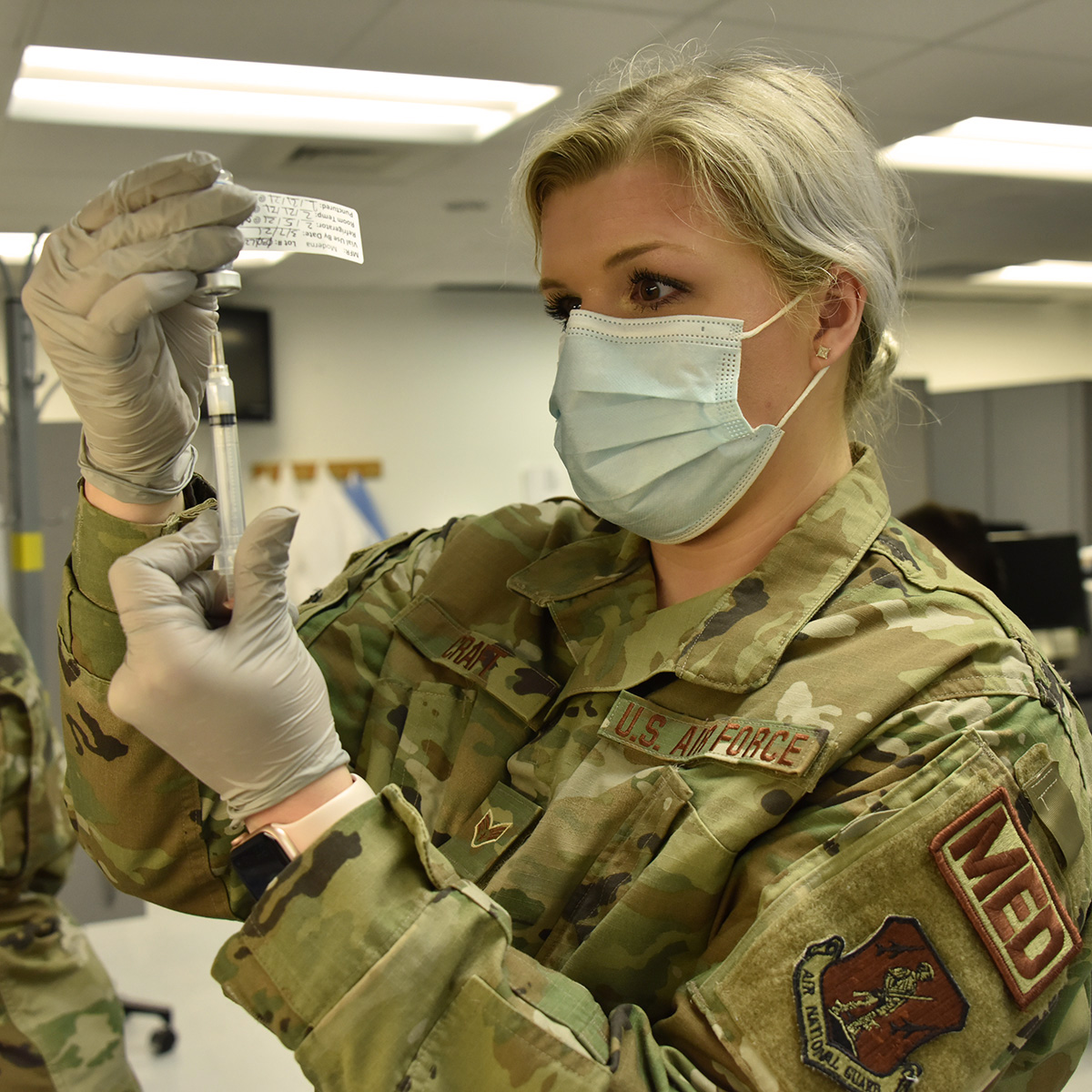 Senior Airman Skyler Craft prepares syringes with COVID-19 vaccination